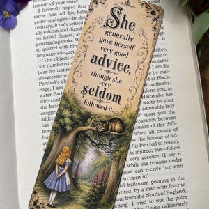May include: A rectangular bookmark featuring a vintage-style illustration of a girl in a blue dress standing in a forest, a cat in a tree, and the text: She generally gave herself very good advice, though she very seldom followed it.