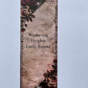 May include: A rectangular bookmark featuring a vintage parchment background with cursive handwriting, ornate dark borders, and clusters of deep red and cream-colored roses at the top and bottom corners. The text reads Wuthering Heights Emily Bront&euml;.