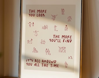 May include: Framed art print with the text "THE MORE YOU LOOK, THE MORE YOU'LL FIND, IT'S ALL AROUND YOU ALL THE TIME" in red. The print features small red illustrations of people. The frame is black and sits on a wooden shelf.