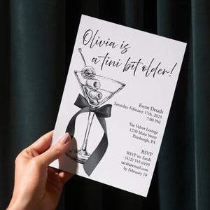 May include: A white invitation card with a martini illustration and the text "Olivia is a tini bit older!". The card includes event details: date, time, location, and RSVP information. A black ribbon is tied around the martini glass.