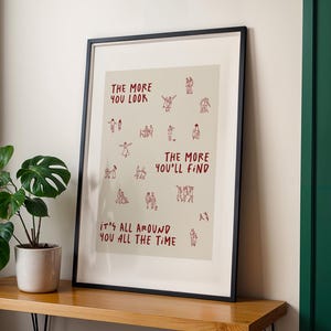 Puede incluir: Impresi&oacute;n art&iacute;stica enmarcada en un marco negro. La impresi&oacute;n tiene un fondo beige con texto e ilustraciones en rojo. El texto dice: "THE MORE YOU LOOK THE MORE YOU'LL FIND IT'S ALL AROUND YOU ALL THE TIME."