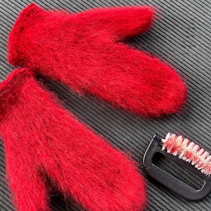Puede incluir: Un par de guantes rojos y peludos con un cepillo negro y blanco para limpiar.