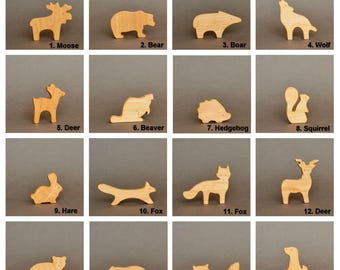 Könnte beinhalten: Eine Sammlung von sechzehn Holzfiguren von Tieren, darunter Elch, Bär, Wildschwein, Wolf, Hirsch, Biber, Igel, Eichhörnchen, Hase, Fuchs, Waschbär und Gopher. Jede Figur ist aus hellem Holz geschnitten und nummeriert.