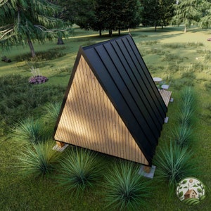 May include: A small, triangular wooden cabin with a black metal roof. The cabin is surrounded by green grass and trees.