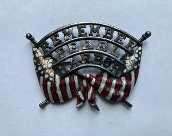 May include: Vintage metal pin with the words "REMEMBER PEARL HARBOR" arched across the top. The pin features two American flags with red and white stripes and white stars.