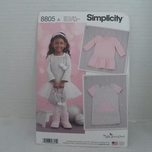 May include: Simplicity sewing pattern 8805 A for girls' clothing. The pattern includes designs for a dress and a top. The image shows a girl wearing a dress and holding a purse. The pattern is designed and printed in the USA.