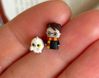 May include: Tiny figurines of Harry Potter and Hedwig. Harry wears glasses, a black robe, and a red and gold scarf. Hedwig is white with yellow details. These miniature figures are highly detailed and ideal for fans of the wizarding world.