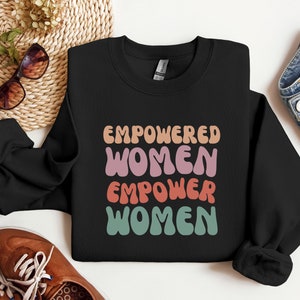 May include: Black sweatshirt with the text "EMPOWERED WOMEN EMPOWER WOMEN" in colorful, retro-style lettering.