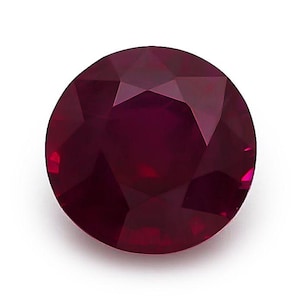 Puede incluir: Una piedra preciosa redonda y facetada de color rojo intenso y saturado. La piedra presenta un corte brillante con múltiples facetas triangulares y en forma de cometa que reflejan la luz, creando una apariencia clara y transparente.