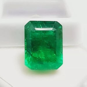 Op de afbeelding: Een levendige, rechthoekig geslepen smaragd edelsteen. De edelsteen heeft een diepe, rijke groene kleur met zichtbare interne insluitsels. De smaragd is geplaatst tegen een witte achtergrond, wat de helderheid en schittering benadrukt. Ideaal voor sieraden.
