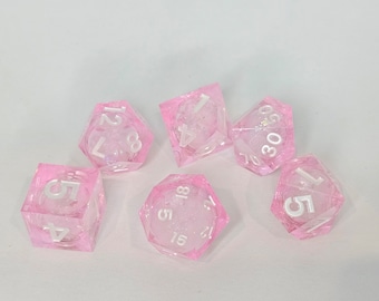 May include: Set of six pink translucent dice with white numbers. The dice are a d4, d6, d8, d10, d12, and d20.