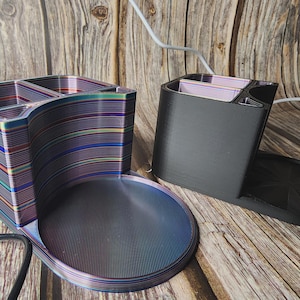May include: Two desk organizers. One is a multi-colored, striped design with a curved shape and a round base. The other is black with a round base. Both have compartments for pens and other office supplies.