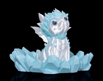 May include: A 3D-printed fantasy figurine of a baby dragon, in a sitting position, with a light blue and white colour scheme. The dragon is perched on a light blue, crystalline base, with a black background.
