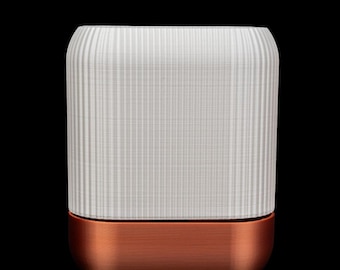 Puede incluir: Una maceta de cerámica blanca con una base de color cobre. La maceta tiene una textura acanalada.