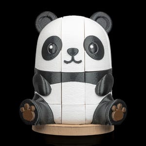 May include: A 3D-printed panda bear puzzle in black, white, and brown. The panda has large black eyes, ears, and paws. It is sitting on a small, round wooden base. The puzzle is made of several interlocking pieces.