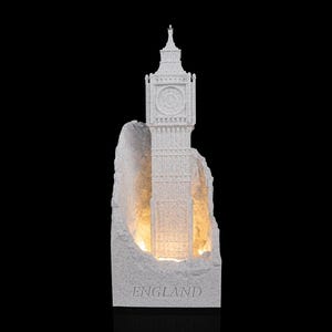 May include: A white, textured, stone-effect sculpture of the Elizabeth Tower, commonly known as Big Ben, set against a jagged, rock-like backdrop. The structure is illuminated from within, and the word ENGLAND is embossed at the base.