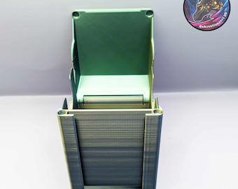 Puede incluir: Una caja de baraja de cartas impresa en 3D de color verde y dorado con una tapa con bisagras. La caja está abierta y la tapa está levantada.