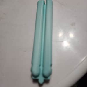 May include: A light blue hair straightener with a rounded handle and a smooth, matte finish.