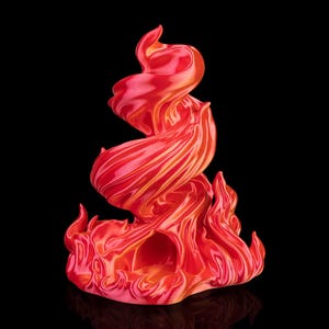 Puede incluir: Una vibrante escultura abstracta en tonos rojos y naranjas, que recuerda a las llamas. La obra de arte tiene una forma arremolinada y dinámica con un acabado brillante, sobre un fondo negro. La base de la escultura tiene un diseño en forma de llama.