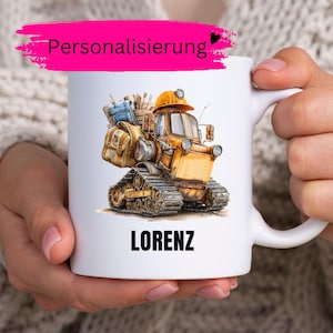 Può includere: Tazza in ceramica bianca con un disegno a cartoni animati di un veicolo da costruzione nei toni del giallo, marrone e blu. La tazza ha il nome "LORENZ" stampato in nero. La parola "Personalisierung" è scritta in rosa in alto.