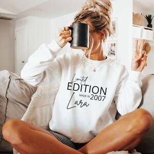 May include: A white long-sleeve sweatshirt featuring black text that reads Limited EDITION MADE IN 2007 and the name Lara in a script font. The garment has a crew neckline and ribbed cuffs, providing a clean and simple look for casual wear.