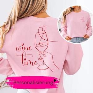 Könnte beinhalten: Ein hellrosa Sweatshirt mit Rundhalsausschnitt und einer roten Strichgrafik auf der Rückseite, die eine Hand mit einem Weinglas, ein Herz und den Schriftzug "wine time" zeigt. Auf der Vorderseite ist das Motiv kleiner mit dem Namen "Sophia".