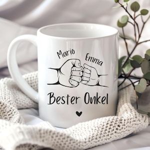 Può includere: Una tazza in ceramica bianca con un'illustrazione a linee nere che raffigura una mano grande e una piccola che si danno il cinque a pugno. Sopra le mani ci sono i nomi Mario ed Emma, sotto il testo Bester Onkel con un piccolo cuore nero.
