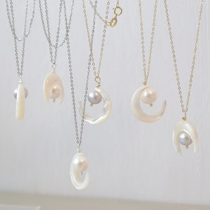 May include: Five necklaces with crescent moon pendants and pearls. The pendants are made of white shell and the pearls are white and gray. The chains are silver and gold.