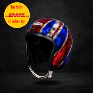 May include: A Union Jack design motorcycle helmet in red, white, and blue. The helmet has a black interior and trim, with a chin strap. The word "CHAMBER" is printed on the helmet.