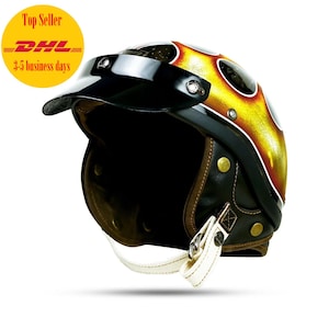 Può includere: Un casco da moto nero con un design a fiamma giallo e rosso. Il casco ha una visiera nera e un cinturino in pelle marrone per il mento.