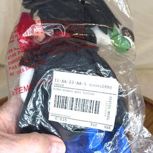 K&ouml;nnte beinhalten: Eine Minnie Mary Poppins Puppe in einer Plastikt&uuml;te. Die Puppe hat einen schwarzen Hut, schwarze Haare, eine rote Schleife und ein blaues Kleid. Die Verpackung enth&auml;lt ein Produktetikett mit Barcode und Artikelnummer.