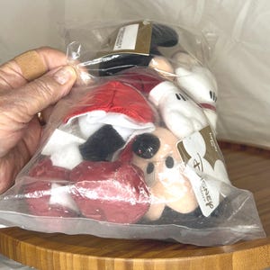 May include: A clear plastic bag containing several Mickey Mouse plush toys. The toys have black ears, red shorts, white gloves, and black shoes. The Disney Store tag is visible.