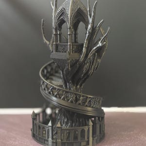Pode incluir: Uma escultura g&oacute;tica cinza escuro de um gazebo no topo de uma &aacute;rvore. O gazebo apresenta um telhado e uma varanda detalhados, com uma escada em espiral descendo pelo tronco. A base &eacute; cercada por uma cerca decorativa.
