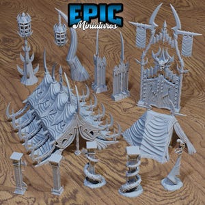 May include: A set of 3D printed miniature dungeon scenery pieces, including a tent, towers, and a gate. The pieces are painted in a light gray color and have a detailed design.