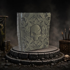 May include: A decorative book with a skull design on the cover. The cover features an ornate floral pattern and a skull in the center. The book is displayed on a stone pedestal, with paint brushes and a skull nearby.