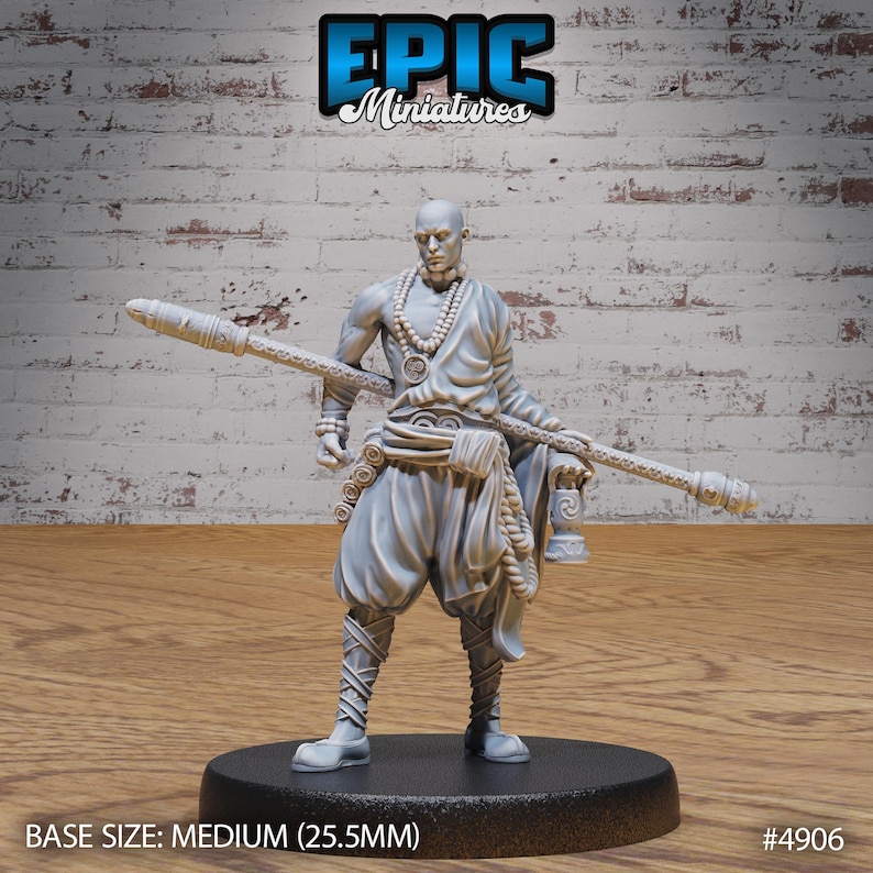 May include: A gray painted miniature figurine of a person wearing a robe and holding a staff. The figurine is standing on a black circular base. The base has the text "BASE SIZE: MEDIUM (25.5MM)" and "#4906".