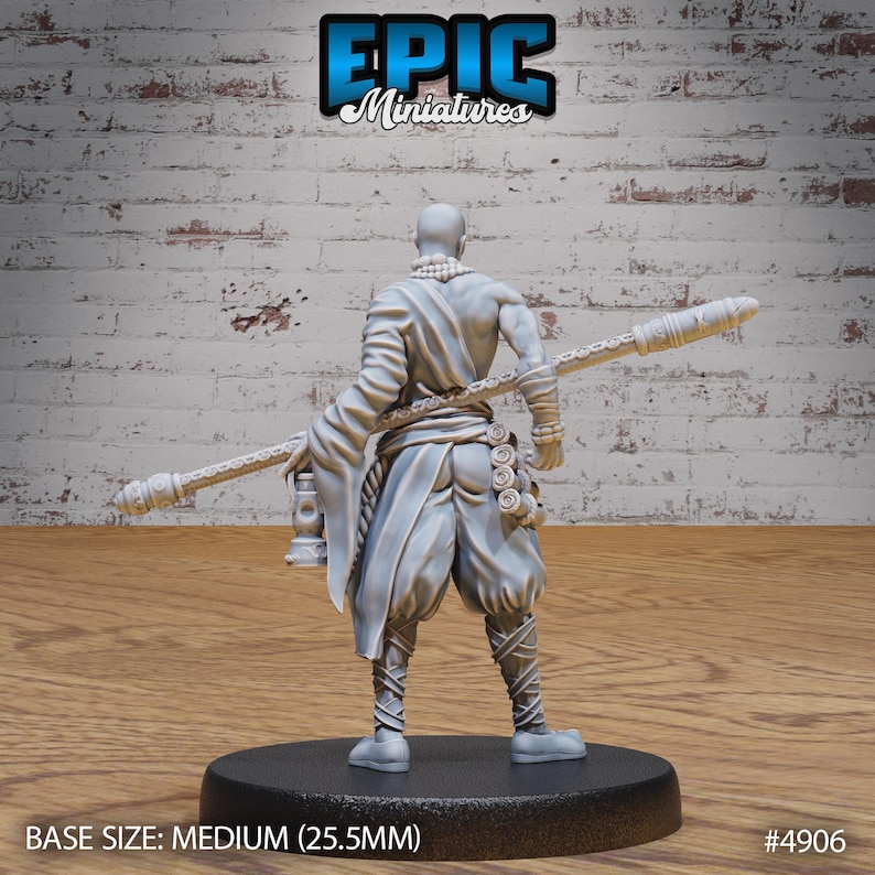 May include: A gray plastic miniature figurine of a person wearing a robe and holding a staff. The figurine is standing on a round base. The base is labeled "BASE SIZE: MEDIUM (25.5MM)" and "#4906".