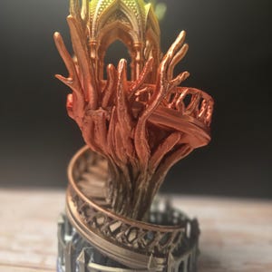 Pode incluir: Escultura detalhada e multicolorida impressa em 3D de uma cidade &eacute;lfica em &aacute;rvore. A escultura apresenta uma escada em espiral, uma estrutura semelhante a uma &aacute;rvore e uma estrutura semelhante a um gazebo no topo. As cores variam de dourado a laranja e castanho.