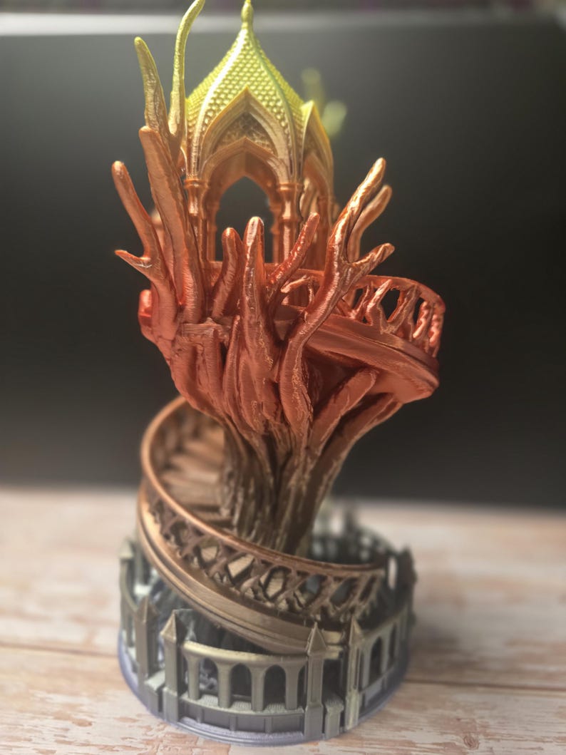 Pode incluir: Escultura detalhada e multicolorida impressa em 3D de uma cidade &eacute;lfica em &aacute;rvore. A escultura apresenta uma escada em espiral, uma estrutura semelhante a uma &aacute;rvore e uma estrutura semelhante a um gazebo no topo. As cores variam de dourado a laranja e castanho.