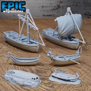 May include: Five miniature wooden boats, painted gray, with various styles and details. Some boats have sails, oars, and lanterns. One boat is partially submerged in sand.