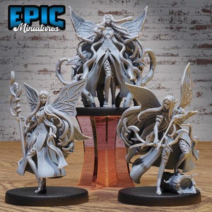 May include: Three gray miniature fantasy figures. One figure stands with a staff, another with a bow and arrow, and a third figure is centered on a decorative stand. The figures have long hair and wings. The text "EPIC Miniatures" is in the upper left corner.