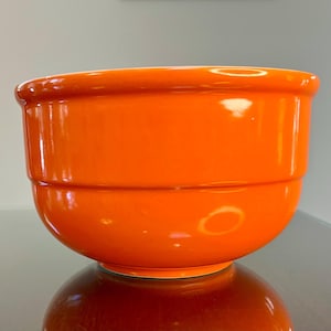Op de afbeelding: Een helder oranje keramische mengkom met een afgeronde bodem en een licht uitlopende rand.