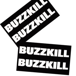 May include: Two black rectangular stickers with the word "BUZZKILL" in bold white capital letters. The word is repeated twice on each sticker. The stickers are angled and overlapping against a white background.