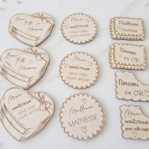 Può includere: Etichette regalo in legno con testo inciso. Le etichette a forma di cuore riportano la scritta "Bonne Fête Maman" e "Merci maîtresse pour cette super année". Altre etichette sono rotonde e smerlate.