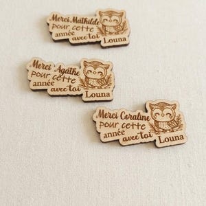 Peut inclure: Trois découpes en bois clair avec une illustration de hibou gravée et le texte Merci Mathilde, Merci Agathe ou Merci Coraline, pour cette année avec toi, Louna. Chaque pièce présente une finition lisse et des bords brun foncé.