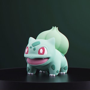 May include: A light green Bulbasaur figurine with red eyes and a pink mouth. The figure has a large bulb on its back and is set against a dark green background. The figurine is on a black surface.