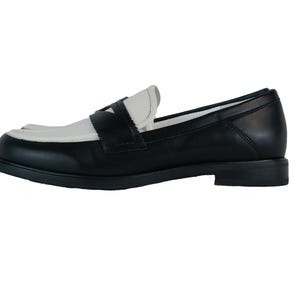 May include: Black leather loafers with a white leather toe and a contrasting black leather strap across the vamp.