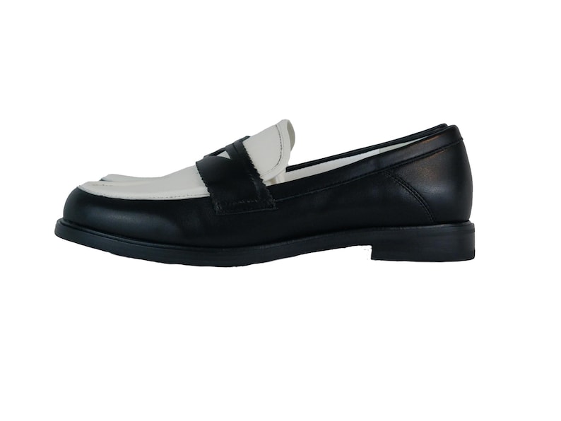 May include: Black leather loafers with a white leather toe and a contrasting black leather strap across the vamp.