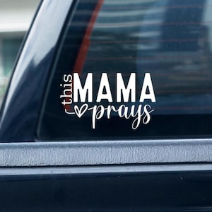 May include: White vinyl decal with the text "this mama prays" and a small heart symbol.