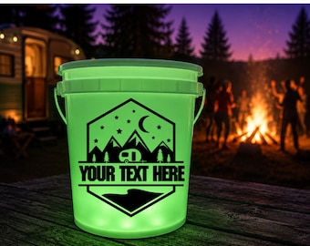May include: A glowing light green plastic bucket featuring a black graphic design of a camper, mountains, stars, and a crescent moon. The text "YOUR TEXT HERE" is printed in bold black capital letters across the center of the hexagonal emblem.